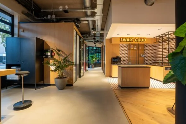 Modern interieur van een kantoorruimte met een koffiebar genaamd "Zwart Goud" en strakke houten en industriële elementen.